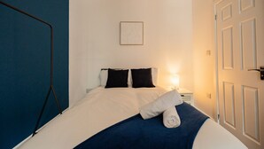 A hotel room with a bed, a nightstand, a lamp, and a door. - 1 Bedroom Studio Apartment Central Middlesbrough (Middlesbrough)
