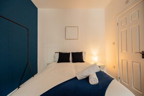Ein Hotelzimmer mit einem Bett, einem Nachttisch, einer Lampe und einer Tür.