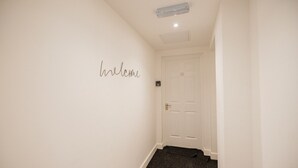 A hallway with a 'welcome' sign on the wall, a door labeled '10', and a carpeted floor. - 1 Bedroom Studio Apartment Central Middlesbrough (Middlesbrough)