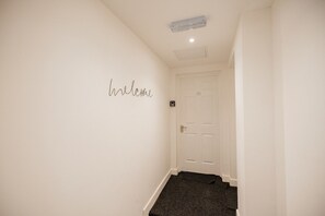 Ein Flur mit einem Schild mit der Aufschrift 'welcome', einer Tür mit der Nummer 10 und einem Teppichboden.
