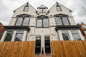 Ein zweistöckiges Haus mit einer symmetrischen Fassade, einem zentralen Eingang und einem Satteldach.