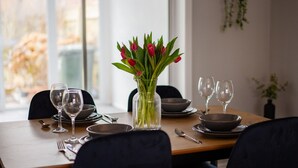 A dining table set with plates, bowls, cutlery, and wine glasses, with a vase of red tulips in the center. - 3 bed Contractor Accommodation Redcar (Redcar)