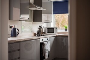 Cozinha moderna equipada com micro-ondas, chaleira e bloco de facas.
