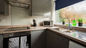 A modern kitchen with a built-in microwave, a sink, and a window with a view of trees. - 3 bed Contractor Accommodation Redcar (Redcar)
