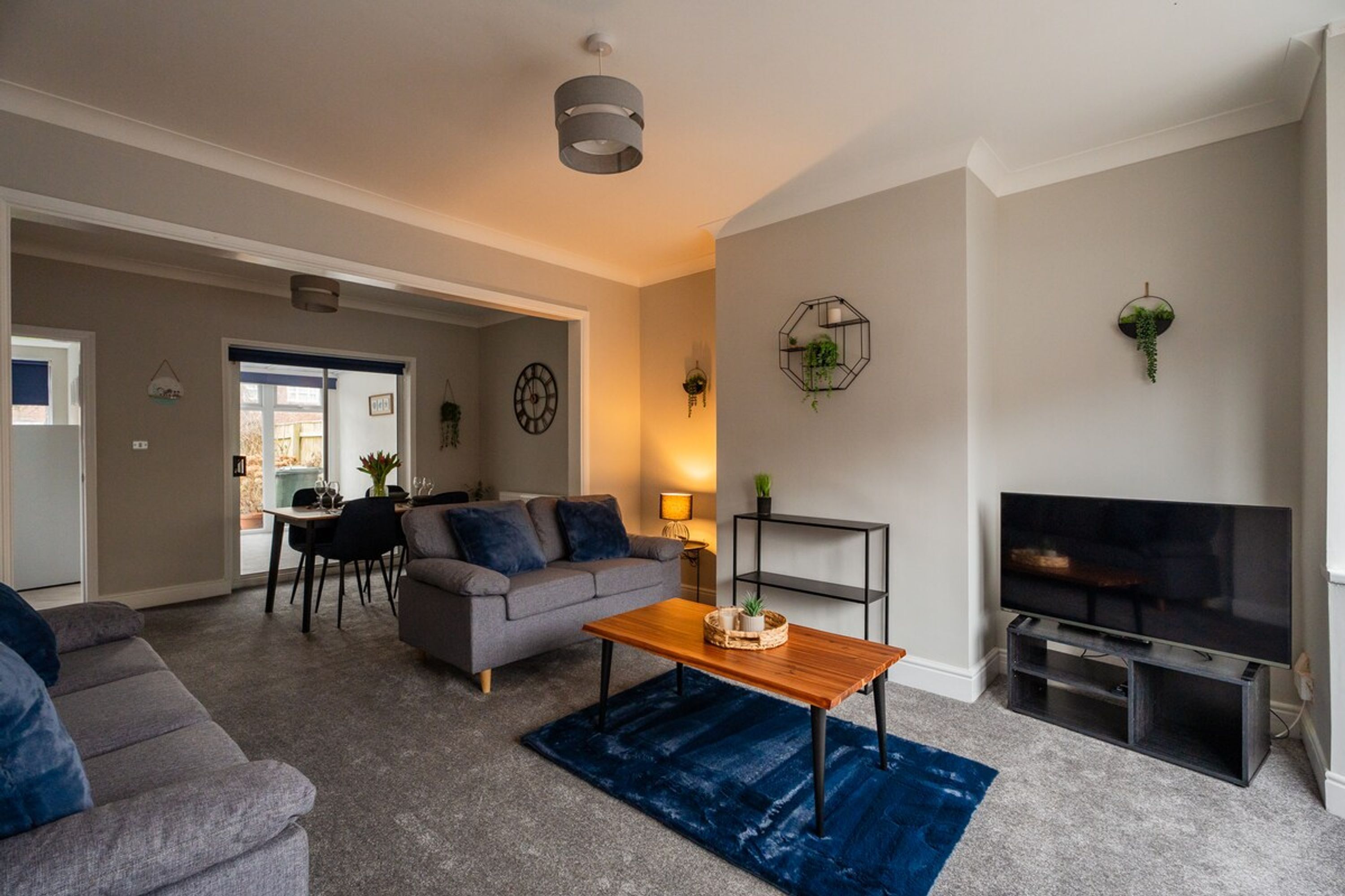 Een woonkamer met een bank, salontafel, televisie en een eethoek met stoelen en een tafel.