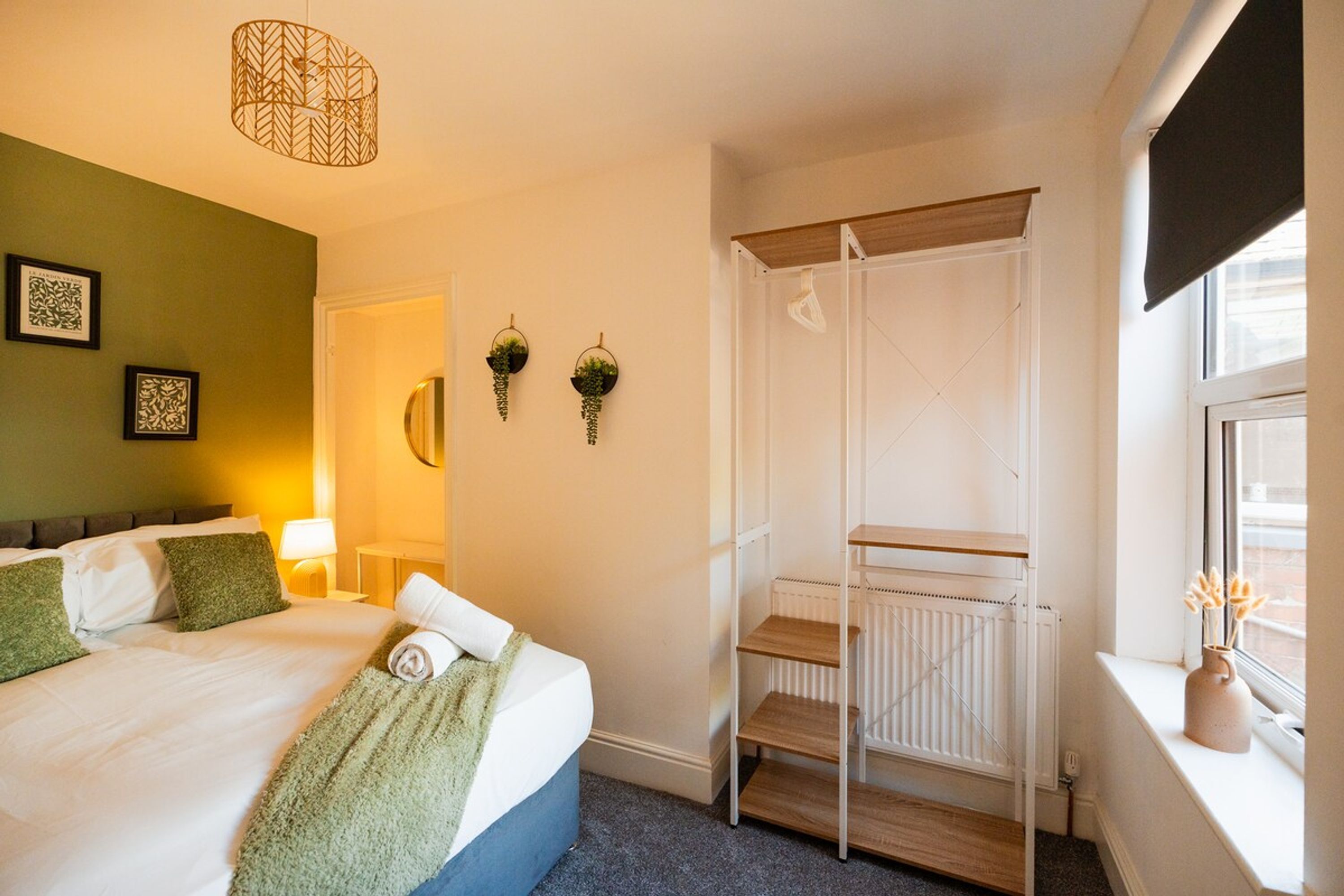 Hotelkamer met een bed, nachtkastje, lamp, raam met uitzicht en een radiator.