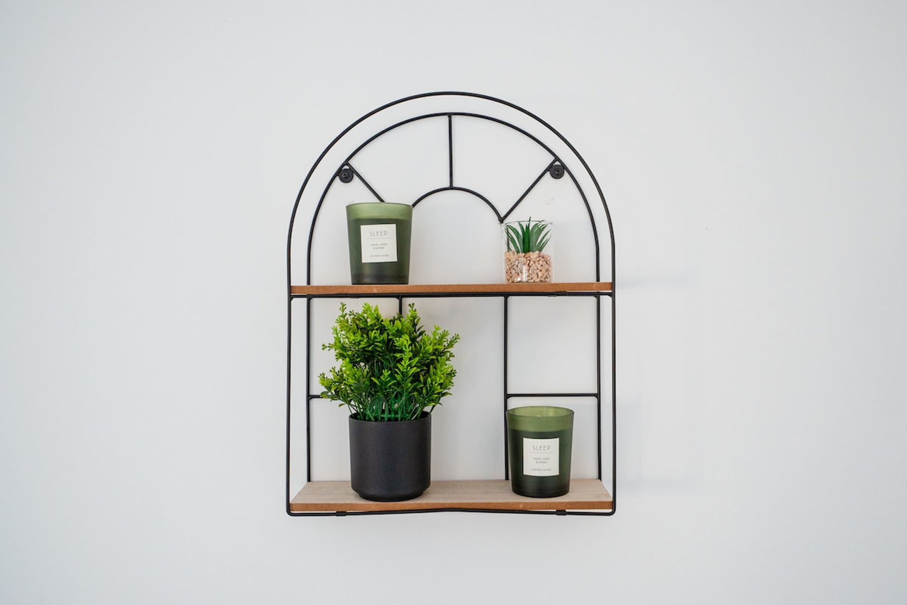 A metal shelf with three compartments, each holding a plant and a candle.