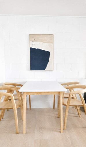 A white table with wooden chairs in a room with white brick walls. - Convenient Townsville Stay Near Hospital and CBD (Pimlico)