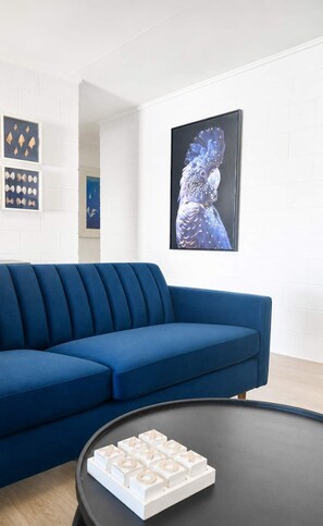 A modern living room with a blue sofa, a black coffee table with a white game, and artwork on the wall. - Convenient Townsville Stay Near Hospital and CBD (Pimlico)