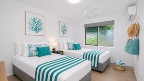 A hotel room with two beds, a ceiling fan, a window with a view, and a wall-mounted air conditioner. - Convenient Townsville Stay Near Hospital and CBD (Pimlico)