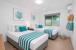 A hotel room with two beds, a ceiling fan, a window with a view, and a wall-mounted air conditioner. - Convenient Townsville Stay Near Hospital and CBD (Pimlico)