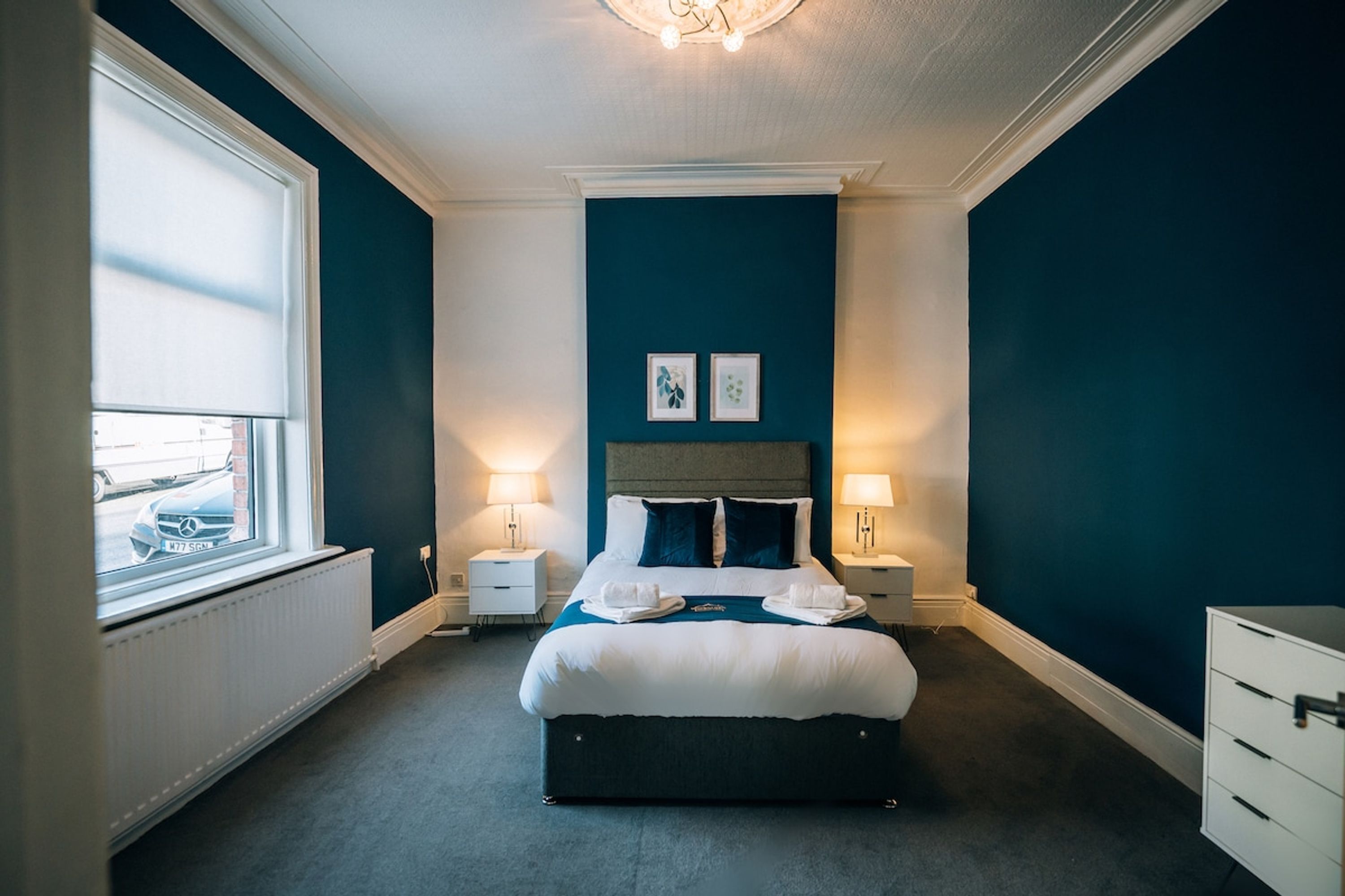 A hotel room with a large bed, bedside tables, a window, and a view of the street.