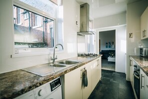 A modern kitchen with a window, stainless steel appliances, and a granite countertop. - Freda House Horizon Stays (Sunderland)