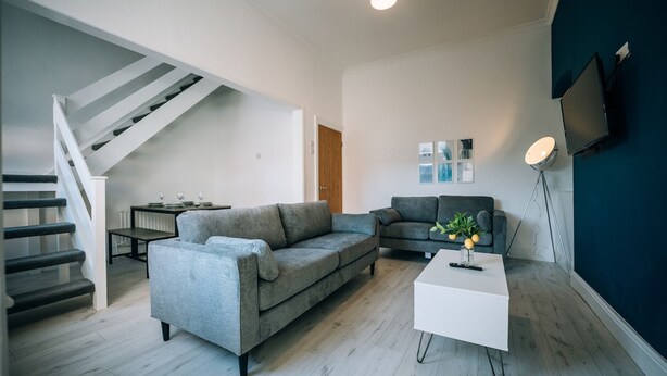 A modern living room with a grey sofa, a white coffee table, and a staircase leading to another level. - Freda House Horizon Stays (Sunderland)