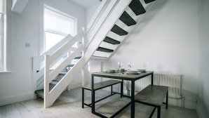 A modern interior with a staircase, a table with chairs, and a radiator. - Freda House Horizon Stays (Sunderland)