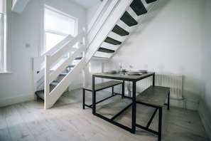 A modern interior with a staircase, a table with chairs, and a radiator. - Freda House Horizon Stays (Sunderland)