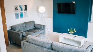 A modern living room with a grey sofa, a white coffee table with a vase, and a floor lamp. - Freda House Horizon Stays (Sunderland)