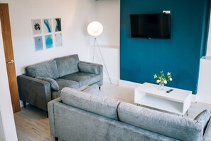 A modern living room with a grey sofa, a white coffee table with a vase, and a floor lamp. - Freda House Horizon Stays (Sunderland)