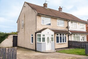 A two-story residential building with a tiled roof, a front porch, and a fenced yard. - Renvyle House Horizon Stays (Stockton-on-Tees)
