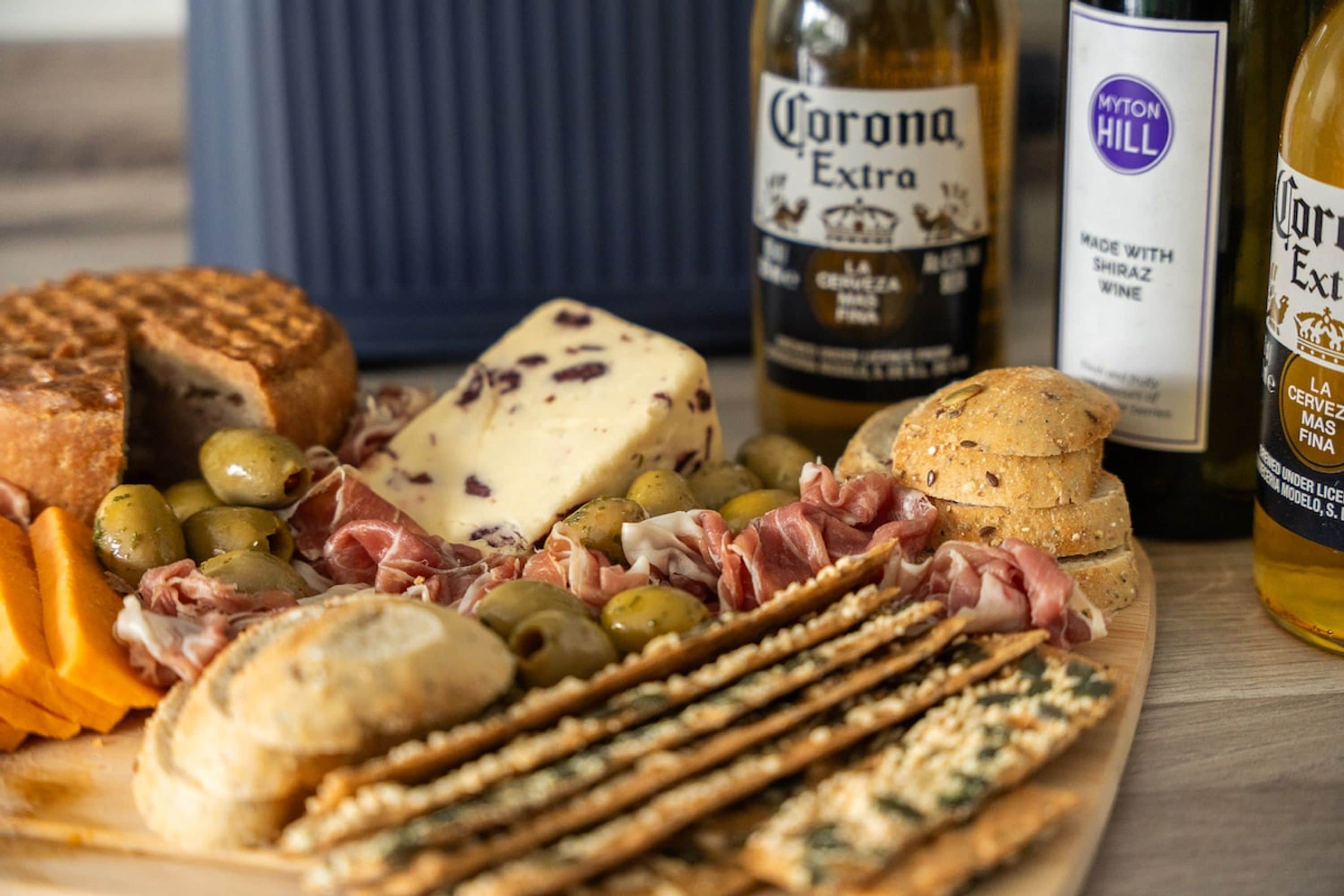A charcuterie board with various cheeses, meats, olives, and crackers.