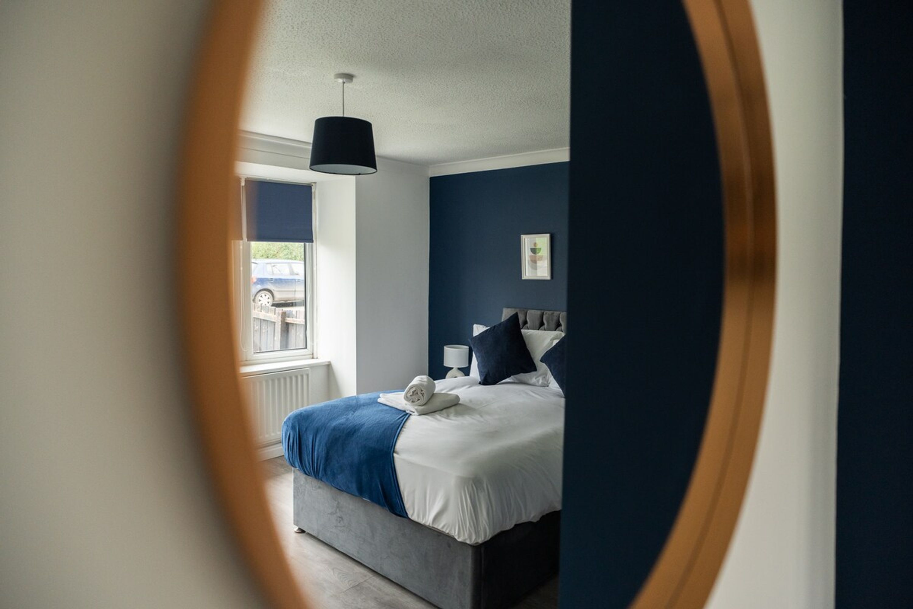 Een slaapkamer met een bed, een raam en een lamp aan de muur.