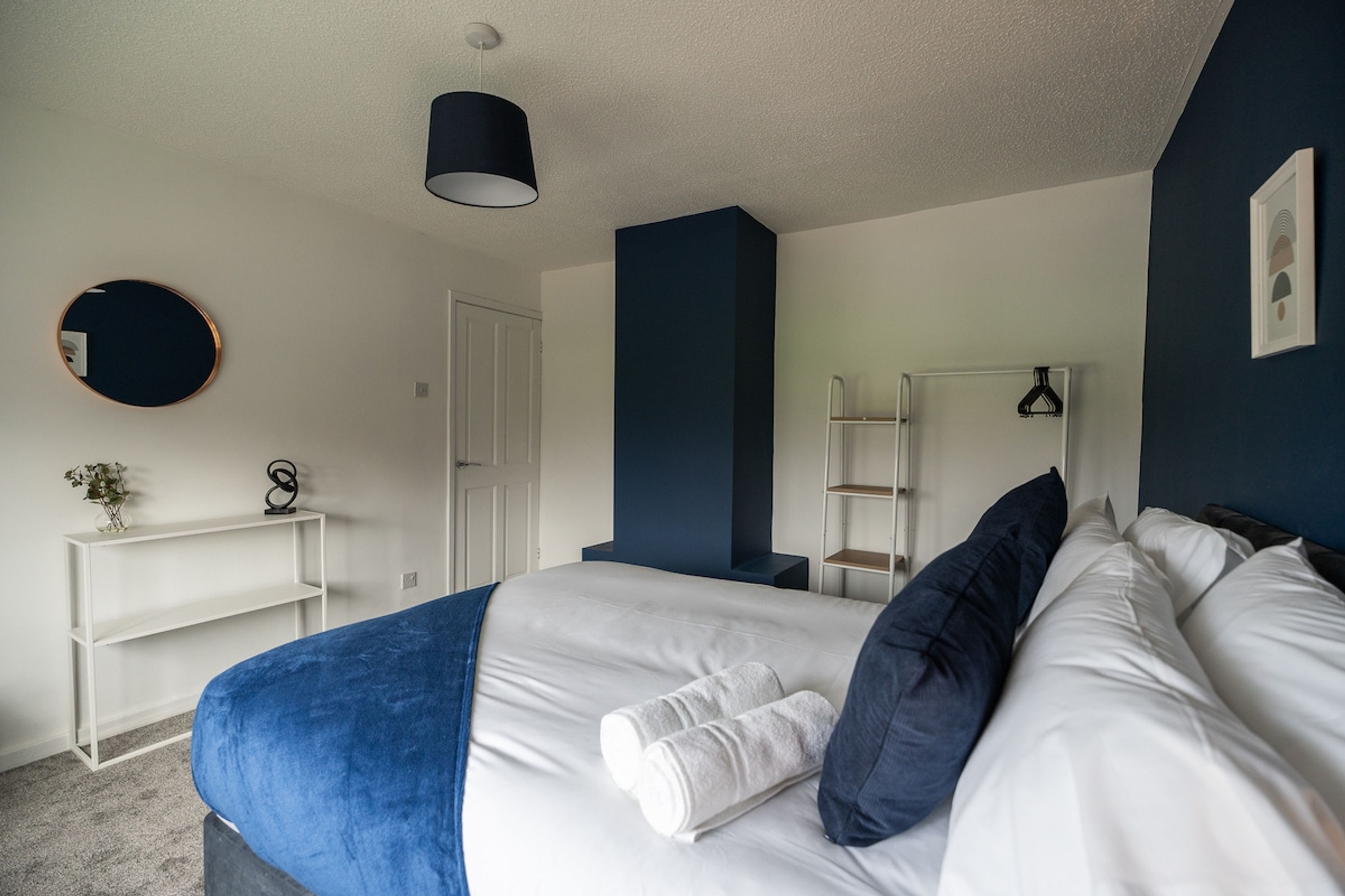 Ein Schlafzimmer mit Bett, Nachttisch, Spiegel und Kleiderschrank.