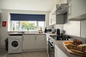 A modern kitchen with a washing machine, a microwave, and a stove. - Renvyle House Horizon Stays (Stockton-on-Tees)