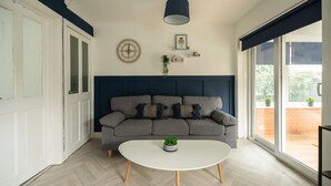 A modern living room with a grey sofa, a white coffee table, and a blue accent wall. - Renvyle House Horizon Stays (Stockton-on-Tees)