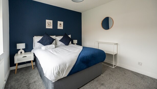 A bedroom with a bed, bedside tables, a desk, and wall art. - Renvyle House Horizon Stays (Stockton-on-Tees)