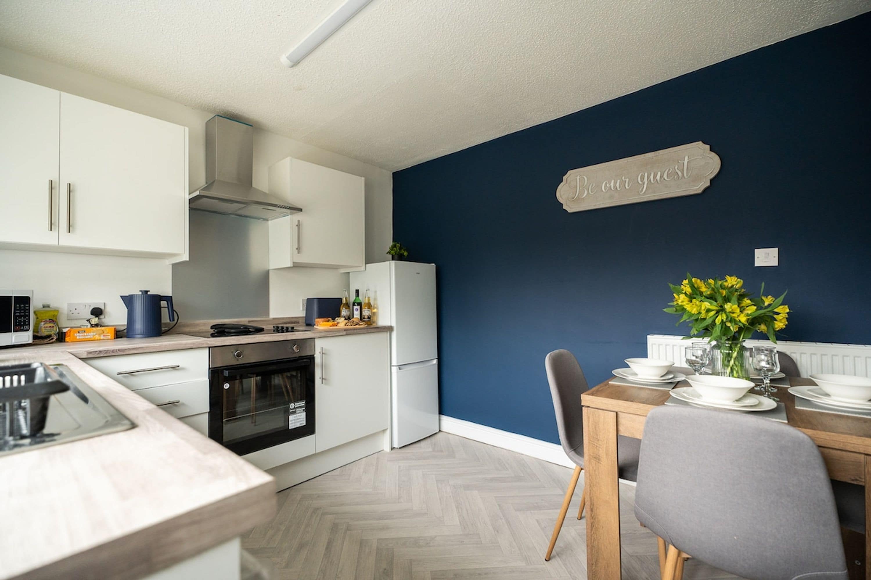 Una cucina moderna con mobili bianchi, forno integrato e frigorifero bianco.