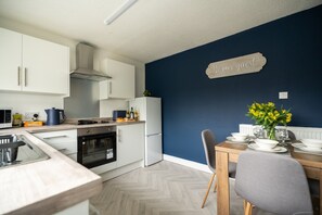 A modern kitchen with white cabinets, a built-in oven, and a white refrigerator. - Renvyle House Horizon Stays (Stockton-on-Tees)
