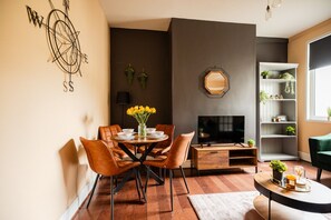 Ein modernes Wohnzimmer mit Essbereich, Flachbildfernseher und Bücherregal.