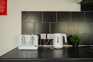 A kitchen counter with a white toaster, a white electric kettle, and a small potted plant. - Jubilee House Horizon Stays (Middlesbrough)