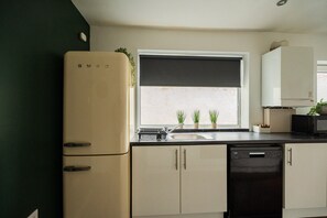 A kitchen with a refrigerator, a sink, cabinets, and a window with blinds. - Jubilee House Horizon Stays (Middlesbrough)