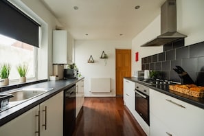 A modern kitchen with a central island, a built-in oven, and a stove. - Jubilee House Horizon Stays (Middlesbrough)