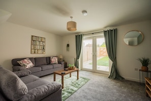 A living room with a grey sofa, a coffee table, and a bookshelf. - Einstein House Horizon Stays (Stockton-on-Tees)