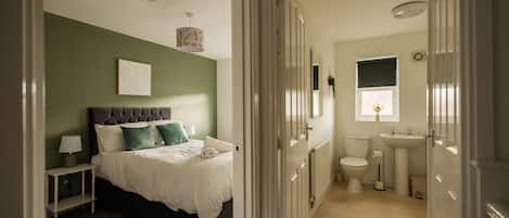 A bedroom with a bed, bedside table, and a hanging light fixture.