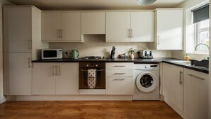 Una cocina equipada con microondas, estufa, horno y lavadora.