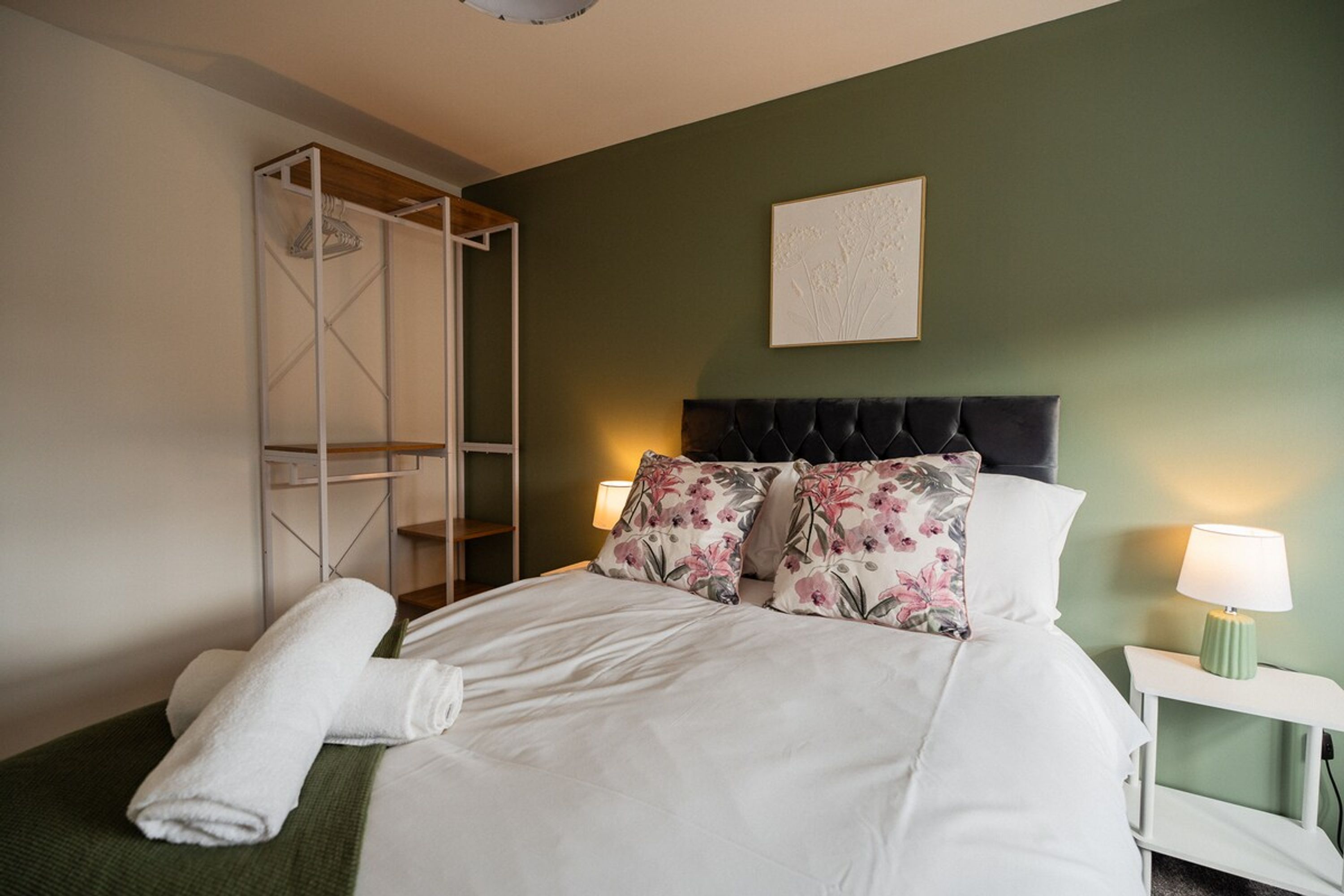 Ein Hotelzimmer mit einem Bett, einem Nachttisch, einer Lampe, einem Wandbild und einem Einbauschrank.