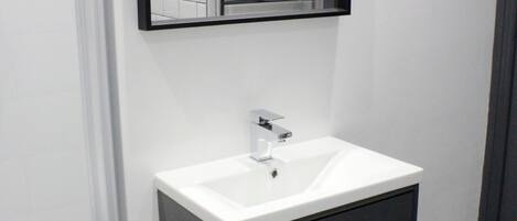 A modern bathroom with a white sink, a mirror, and a towel rack.