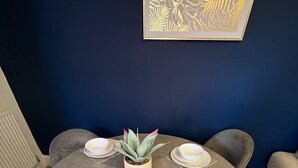 A round table with four plates and a small plant in the center, surrounded by chairs. - Rochester House Horizon Stays (Middlesbrough)
