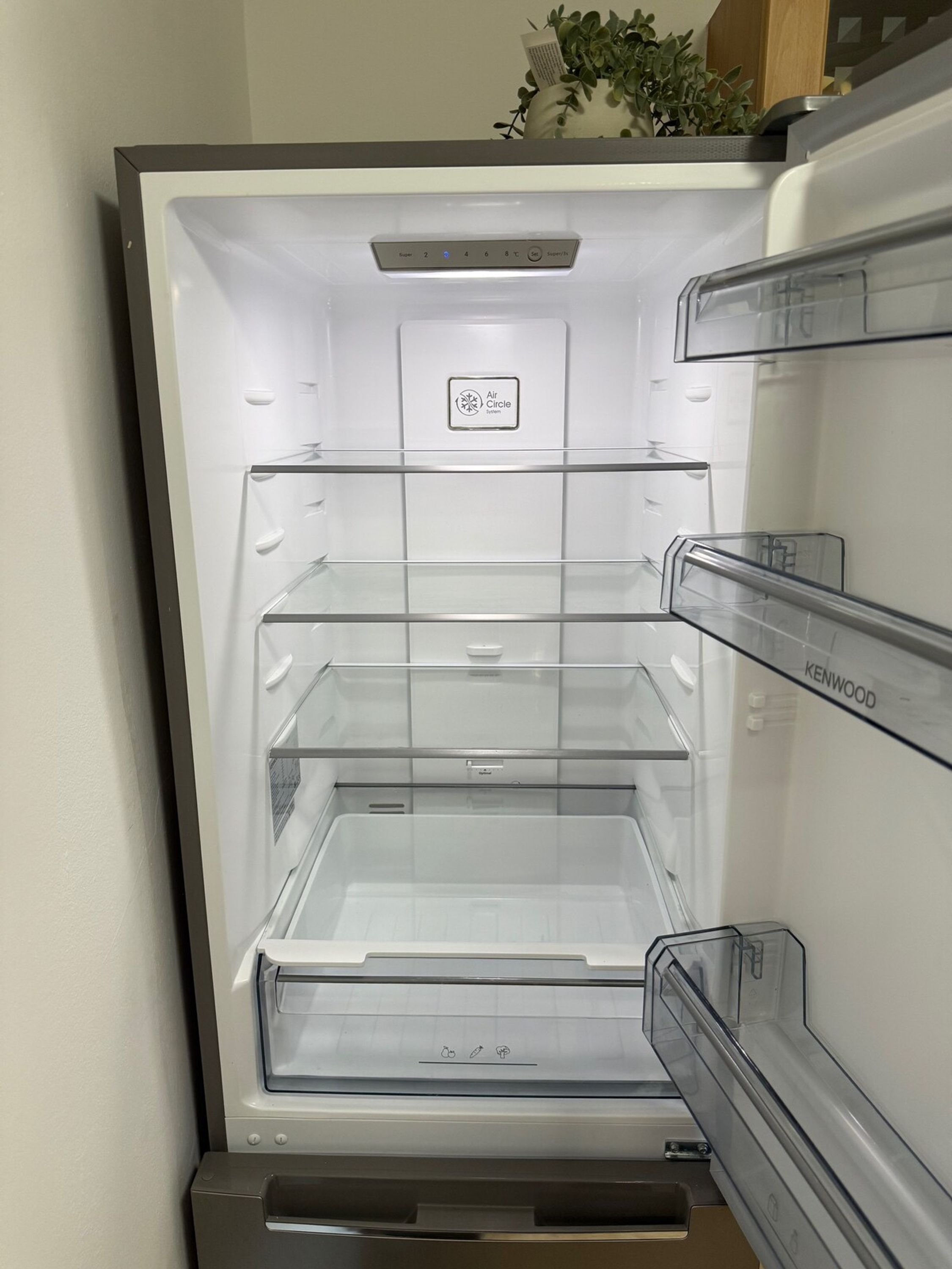 Un frigorifero aperto con tre ripiani trasparenti e un pannello di controllo con impostazioni della temperatura.