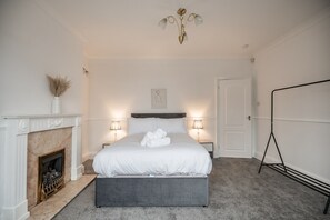 A bedroom with a bed, bedside lamps, a fireplace, and a standing lamp. - Rochester House Horizon Stays (Middlesbrough)