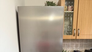 A stainless steel refrigerator in a kitchen with wooden cabinets and a tiled backsplash. - Rochester House Horizon Stays (Middlesbrough)