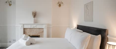 A hotel room with a bed, a fireplace, and a wall-mounted artwork.