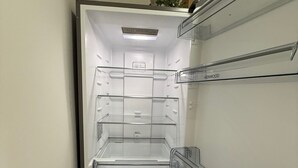 An interior view of a Kenwood refrigerator with multiple shelves and a freezer compartment. - Rochester House Horizon Stays (Middlesbrough)