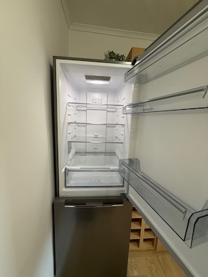 Ein Blick ins Innere eines Kenwood-Kühlschranks mit mehreren Einlegeböden und einem Gefrierfach.