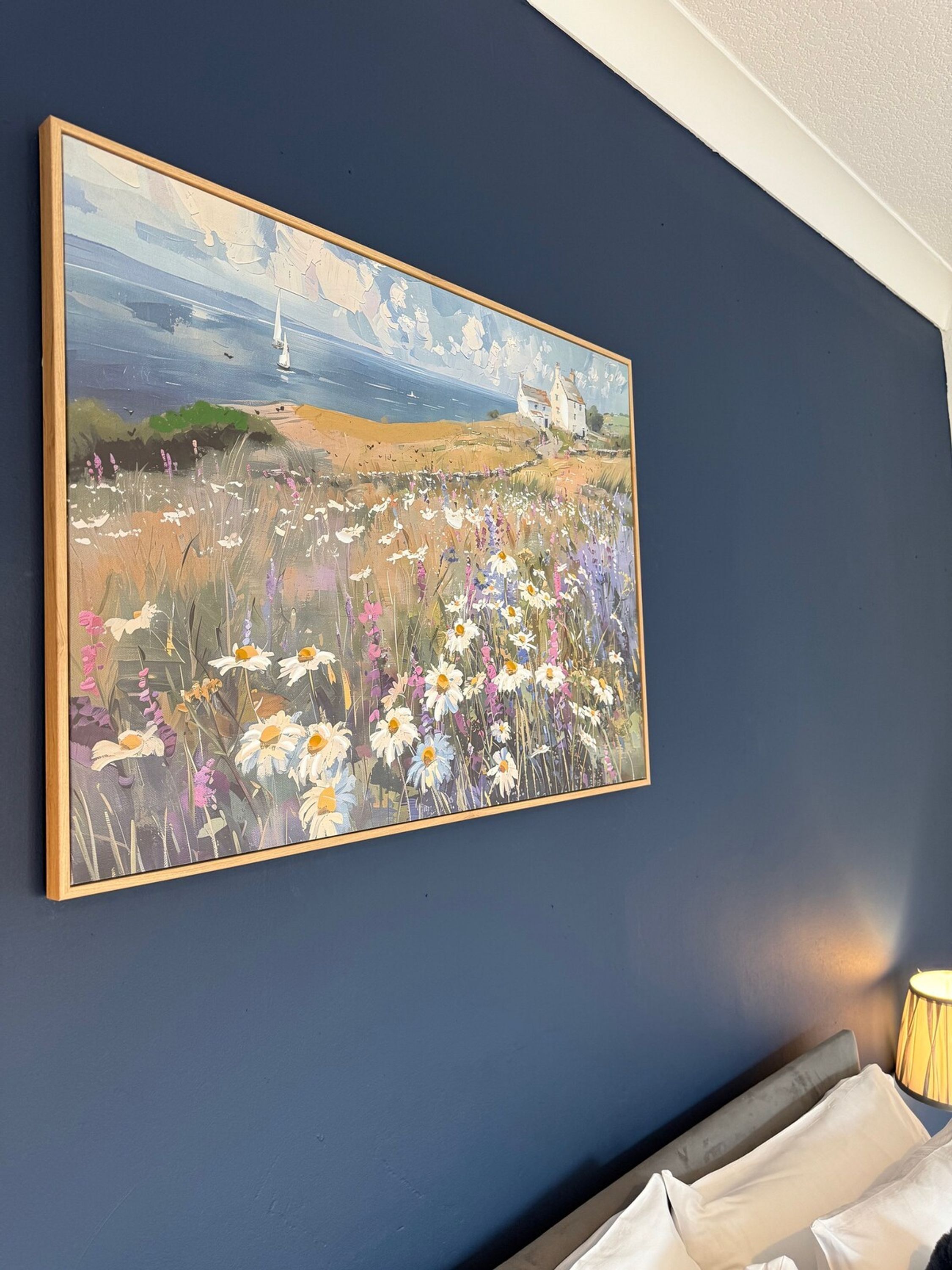 A painting of a field with flowers and a sailboat on a blue wall.