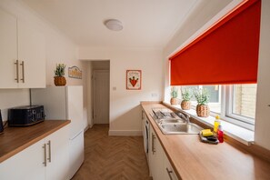Eine moderne Küche mit weißen Schränken, einer Holz Arbeitsplatte, einem Toaster und einem Fenster mit rotem Rollo.