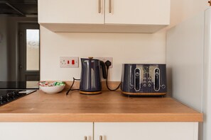 A kitchen with a stove, a kettle, a toaster, and a bowl of cereal on the counter. - The Blue Ember By Horizon Stays (Middlesbrough)